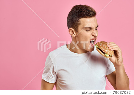 man with big hamburger on pink background calories fast food cropped view Copy Space close-up 79687082