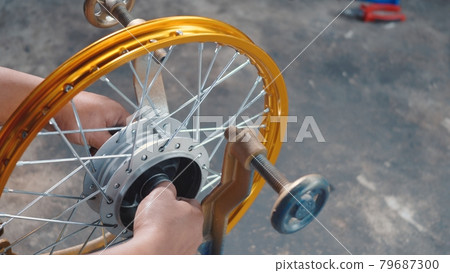 Technician man working motorcycle wheel has spokes weave up on mechanic tool new steel wheel 79687300