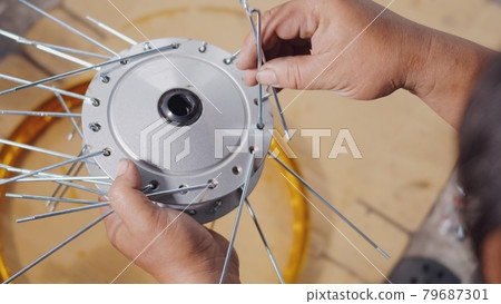 Technician man working motorcycle wheel has spokes weave up on mechanic new steel wheel 79687301