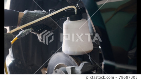 Auto mechanic replacing brake fluid on a vehicle 79687303