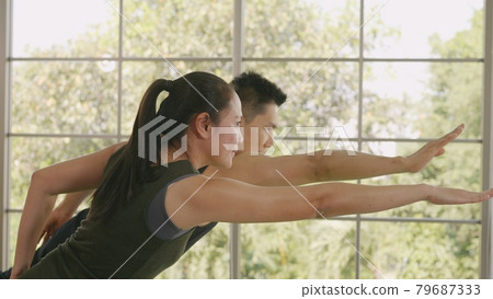 family couple doing YOGA standing meditating on virabhadrasana 3 pose workout 79687333