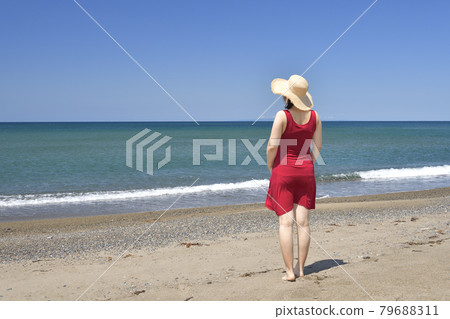 夏季，在北海道江差町五林澤海灘拍攝戴草帽、身穿紅裙的女子肖像 79688311