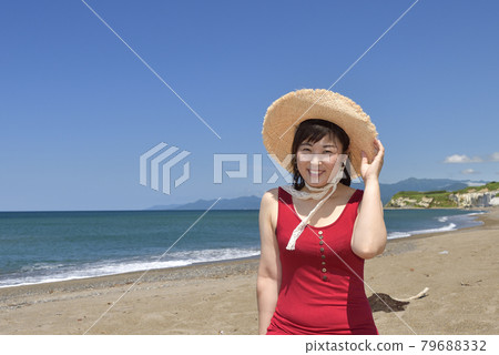 夏季，在北海道江差町五林澤海灘拍攝戴草帽、身穿紅裙的女子肖像 79688332