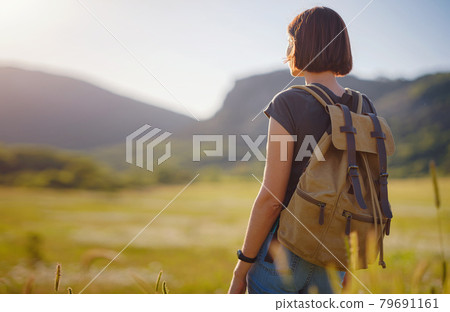 young woman with a backpack in a field at sunset young woman with a backpack in a field at sunset 79691161