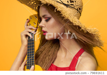 Woman holding Ukulele straw hat lifestyle Exotic yellow background 79691611