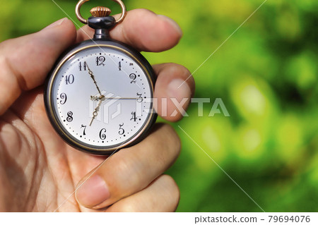 Pocket watch and green blur background Pocket watch and green blur background 79694076