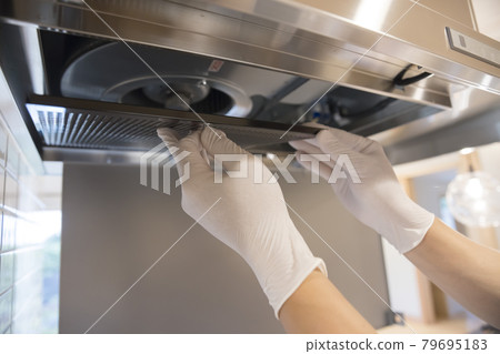 A man replacing a metal filter in a range hood A man replacing a metal filter in a range hood 79695183