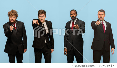 Pointing, choosing. Collage of portraits of four men in dark suits isolated over light blue studio background. Pointing, choosing. Collage of portraits of four men in dark suits isolated over light blue studio background. 79695617