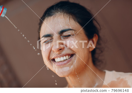 Stressed woman suffering of heatstroke refreshing with cold water outside. Weather abnormal heat concept. 79696148