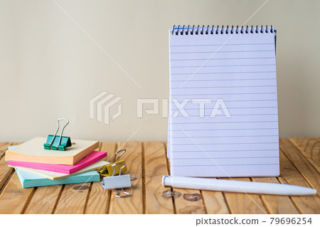 Empty Spiral Notepad With Pen Beside A Stockpile Of Sticky Notes On Top Of A Desk. Blank Notebook With A Ballpen And Stacks Of Note Placed On A Wooden Table. Empty Spiral Notepad With Pen Beside A Stockpile Of Sticky Notes On Top Of A Desk. Blank Notebook With A Ballpen And Stacks Of Note Placed On A Wooden Table. 79696254