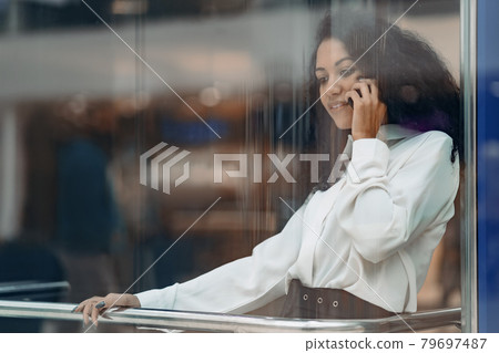 young woman with a smartphone climbing in a glass elevator . 79697487
