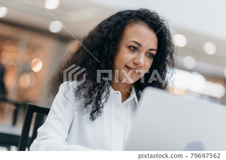 smiling woman runs her blog in the cafeteria of a shopping mall. smiling woman runs her blog in the cafeteria of a shopping mall. 79697562