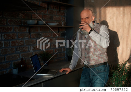 business man with a glass of wine looking at the screen of his laptop. business man with a glass of wine looking at the screen of his laptop. 79697832