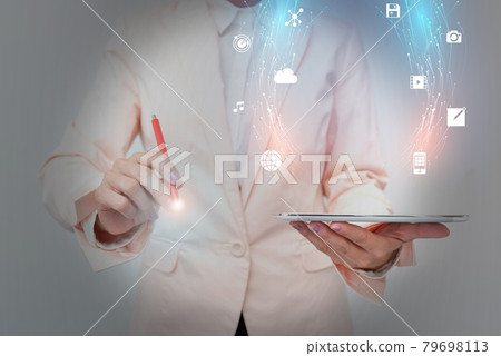 Business Woman Standing And Using Phone While Presenting New Futuristic Virtual Display. Lady In Suit Holding A Mobile Gadget Displaying A Holographic Interface Tech. Business Woman Standing And Using Phone While Presenting New Futuristic Virtual Display. Lady In Suit Holding A Mobile Gadget Displaying A Holographic Interface Tech. 79698113