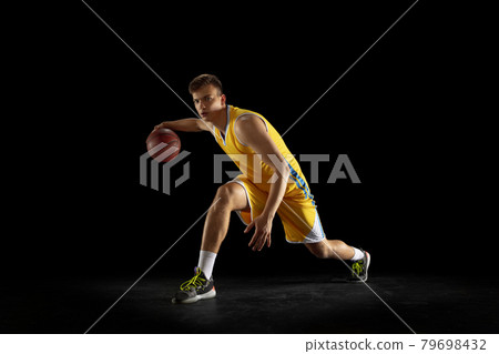 Basketball player with a ball training isolated on dark black studio background. Advertising concept. Fit Caucasian athlete practicing with ball. 79698432