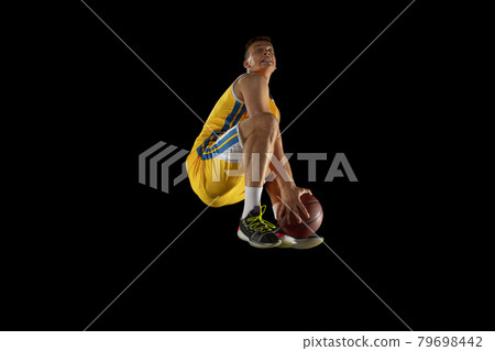 Jump shot. Basketball player with a ball in action and motion isolated on dark black studio background. Advertising concept. Strong Caucasian athlete practicing with basketball ball. Jump shot. Basketball player with a ball in action and motion isolated on dark black studio background. Advertising concept. Strong Caucasian athlete practicing with basketball ball. 79698442