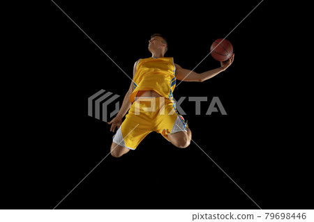 Basketball player with a ball in action and motion isolated on dark black studio background. Advertising concept. Strong Caucasian athlete practicing with basketball ball. Basketball player with a ball in action and motion isolated on dark black studio background. Advertising concept. Strong Caucasian athlete practicing with basketball ball. 79698446