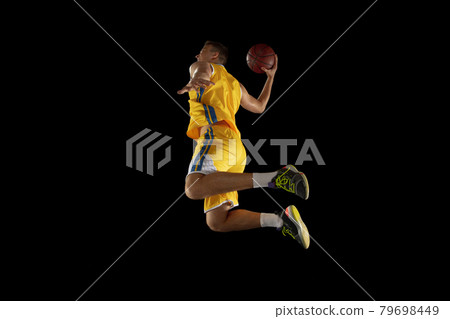 Young man, basketball player with a ball training isolated on dark black studio background. Advertising concept. Fit Caucasian athlete practicing with ball. Young man, basketball player with a ball training isolated on dark black studio background. Advertising concept. Fit Caucasian athlete practicing with ball. 79698449