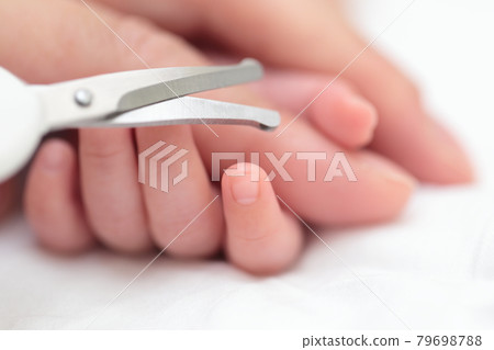 Mom cutting the nails of a newborn baby's hand Mom cutting the nails of a newborn baby's hand 79698788