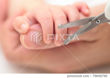 Mom cutting the nails of a newborn baby's hand 79698790