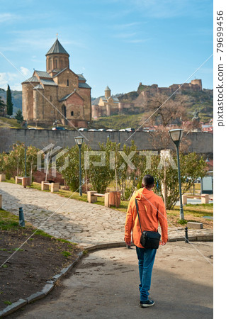 The guy walks up the hill to the Old Georgian-style church. Metekhi monastery in Tbilisi The guy walks up the hill to the Old Georgian-style church. Metekhi monastery in Tbilisi 79699456