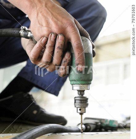 Worker hands making holes with a pneumatic drill on the body plane for further riveting Worker hands making holes with a pneumatic drill on the body plane for further riveting 79701603