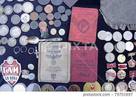 Sertificates of Don cossack serviced in Germany army in 1940s and Red Soviet army soldiers, pile of vintage coins and old Soviet USSR medals placed on a tray for sale 79701697