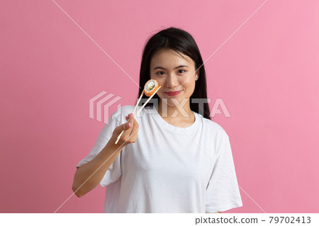 Asian beauty model girl eating Sushi roll, healthy japanese food. Beautiful woman holding chopsticks with Philadelfia roll 79702413