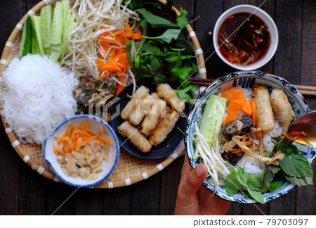 people eating Vietnamese vegan food, rice noodle, fried spring rolls hand hold noodle bowl 79703097