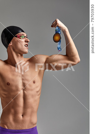 Athlete swimmer with a medal in his hands celebrating a victory, gray background, copy space 79703930
