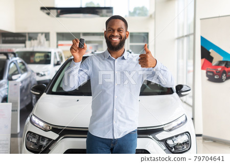 Black Man Standing Near New Car, Holding Key And Showing Thumb Up 79704641