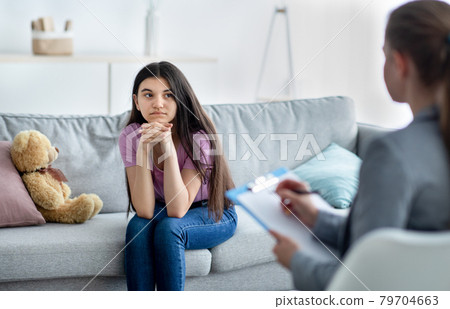 Female psychologist consulting depressed Indian teenage girl at office Female psychologist consulting depressed Indian teenage girl at office 79704663