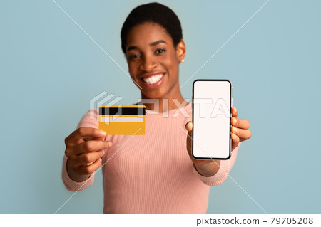 Online Banking App. Cheerful black woman holding credit card and blank smartphone Online Banking App. Cheerful black woman holding credit card and blank smartphone 79705208