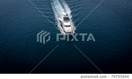 Aerial view of luxury speedboat yacht cruising in deep ocean water. Aerial view of luxury speedboat yacht cruising in deep ocean water. 79705684