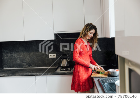 beautiful woman housewife prepares a salad of vegetables in the kitchen beautiful woman housewife prepares a salad of vegetables in the kitchen 79706146