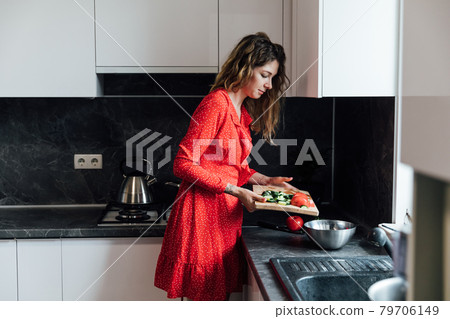 beautiful woman housewife prepares a salad of vegetables in the kitchen beautiful woman housewife prepares a salad of vegetables in the kitchen 79706149
