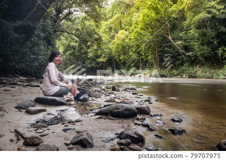 Tourist admiring scenic nature view of Tahan River bank with lush rainforest foliage at Taman Negara National Park, Pahang 79707975