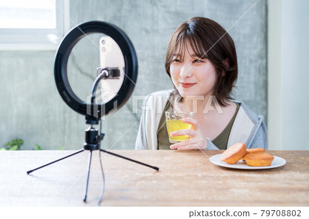 A woman who uses a ring light to live stream in a room 79708802