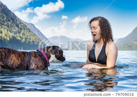 Caucasian Woman swimming in a lake with dog 79709018