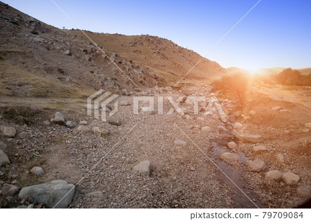 rocky road in the foothills at sunset. Uzbekistan 79709084