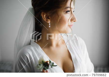 Beautiful bride wearing fashion wedding dress with feathers with luxury delight make-up and hairstyle, studio indoor photo shoot Beautiful bride wearing fashion wedding dress with feathers with luxury delight make-up and hairstyle, studio indoor photo shoot 79709662