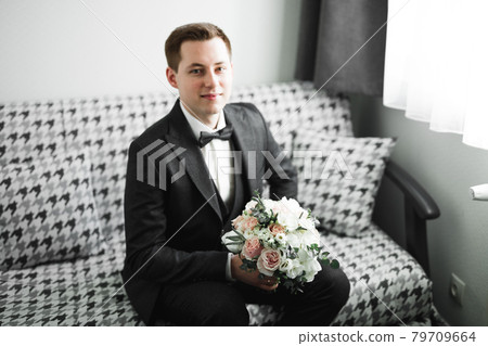 Beautiful man, groom holding big and beautiful wedding bouquet with flowers Beautiful man, groom holding big and beautiful wedding bouquet with flowers 79709664