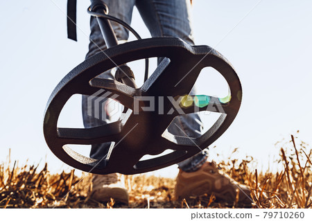 Man with metal detector equipment searching for metal goods in the field 79710260