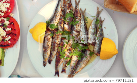 Eating appetizing sardines dish served with parsley and lemon 79711181
