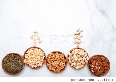 Different kind of nuts in wooden bowls Different kind of nuts in wooden bowls 79711404