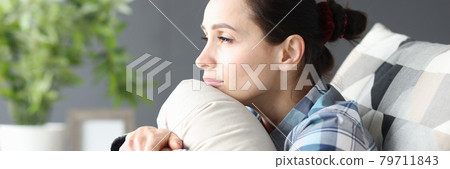 Portrait of young sad woman sitting on couch 79711843
