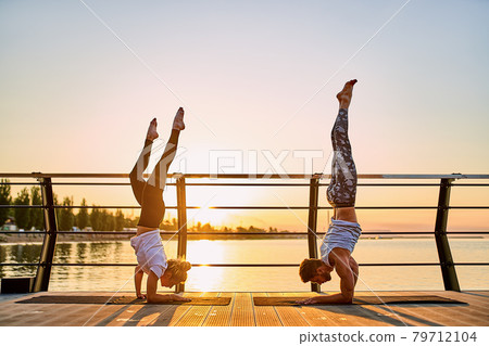 Couple doing practicing yoga together on nature outdoors . Morning exercises at the sunrise. 79712104