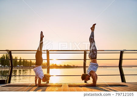 Couple doing practicing yoga together on nature outdoors . Morning exercises at the sunrise 79712105