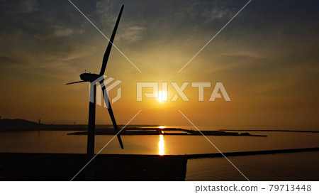 A sunset reflected on the sea surface and the silhouette of a windmill 79713448