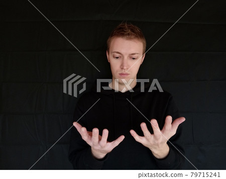 男人看著他的手掌,外國人,黑色背景 男人看著他的手掌,外國人,黑色背景 79715241